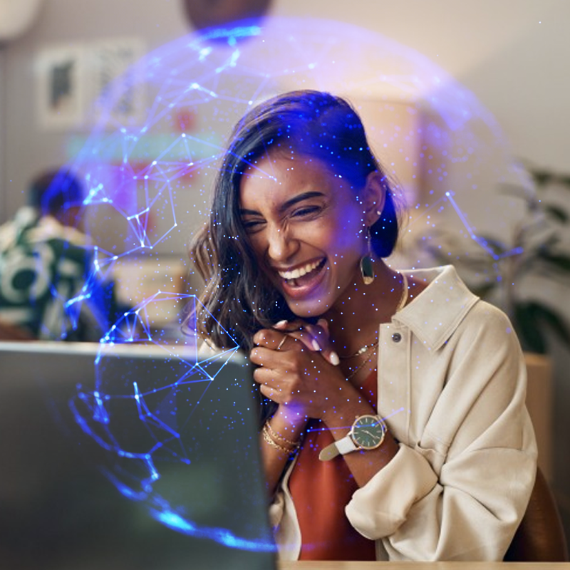 A woman overjoyed at what she is seeing on a laptop. There's a spherical graphics overlay, symbolizing AI-empowered data analytics.